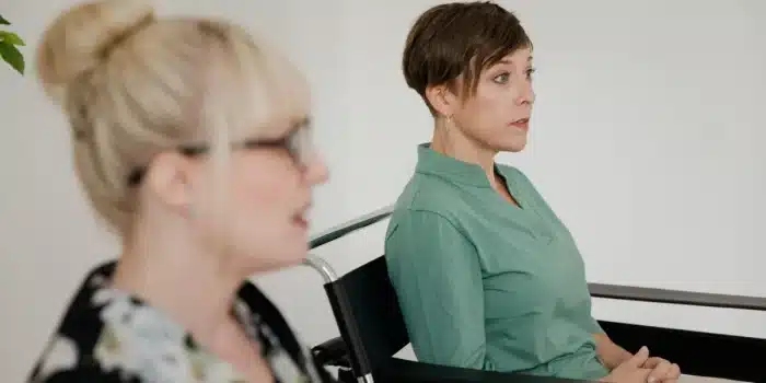 Femme en consultation médicale bienveillante, visage détourné, discussion avec professionnel de santé