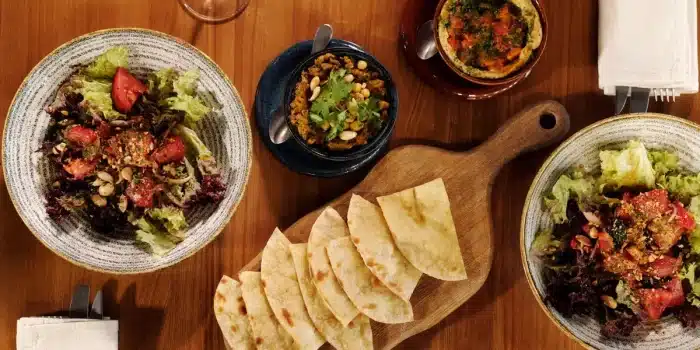 Plateau de mezzé avec tartinades, herbes fraîches, citron et croûtons dorés arrangés dans de petits bols