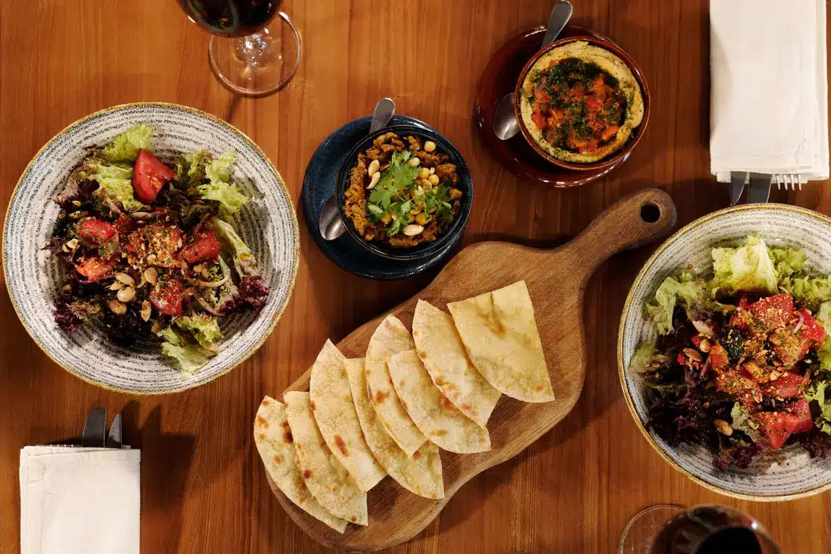 Plateau de mezzé avec tartinades, herbes fraîches, citron et croûtons dorés arrangés dans de petits bols