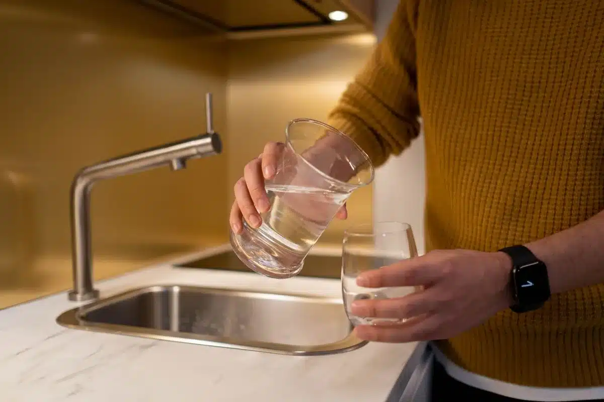 Robinet d'eau du robinet coulant dans un verre transparent en cuisine