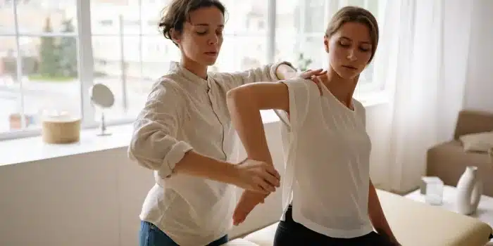 Mains d'un thérapeute effectuant un massage sportif sur l'épaule et le dos d'un athlète