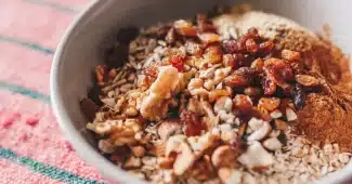 Bol d'overnight oats avec flocons d'avoine, fruits frais et noix sur un plan de travail