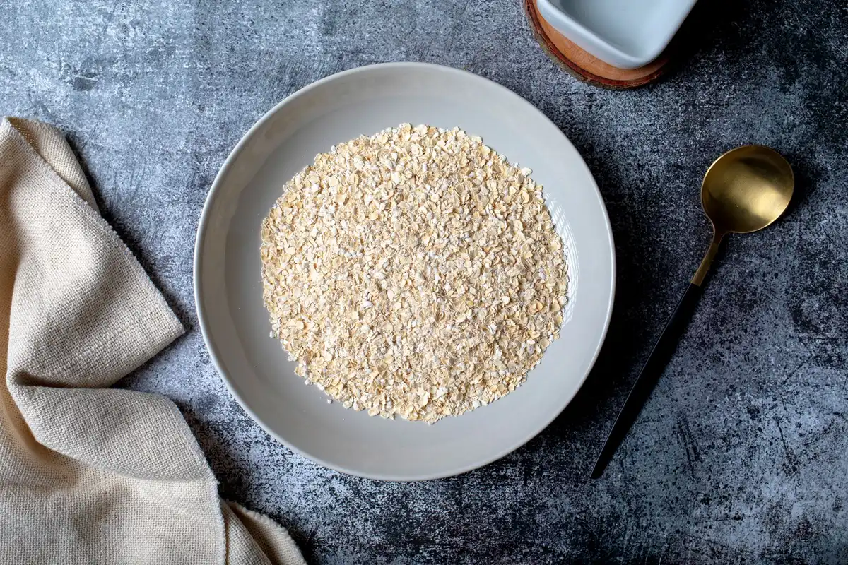 Flocons d'avoine versés dans un bol avec de l'eau pour la préparation du porridge