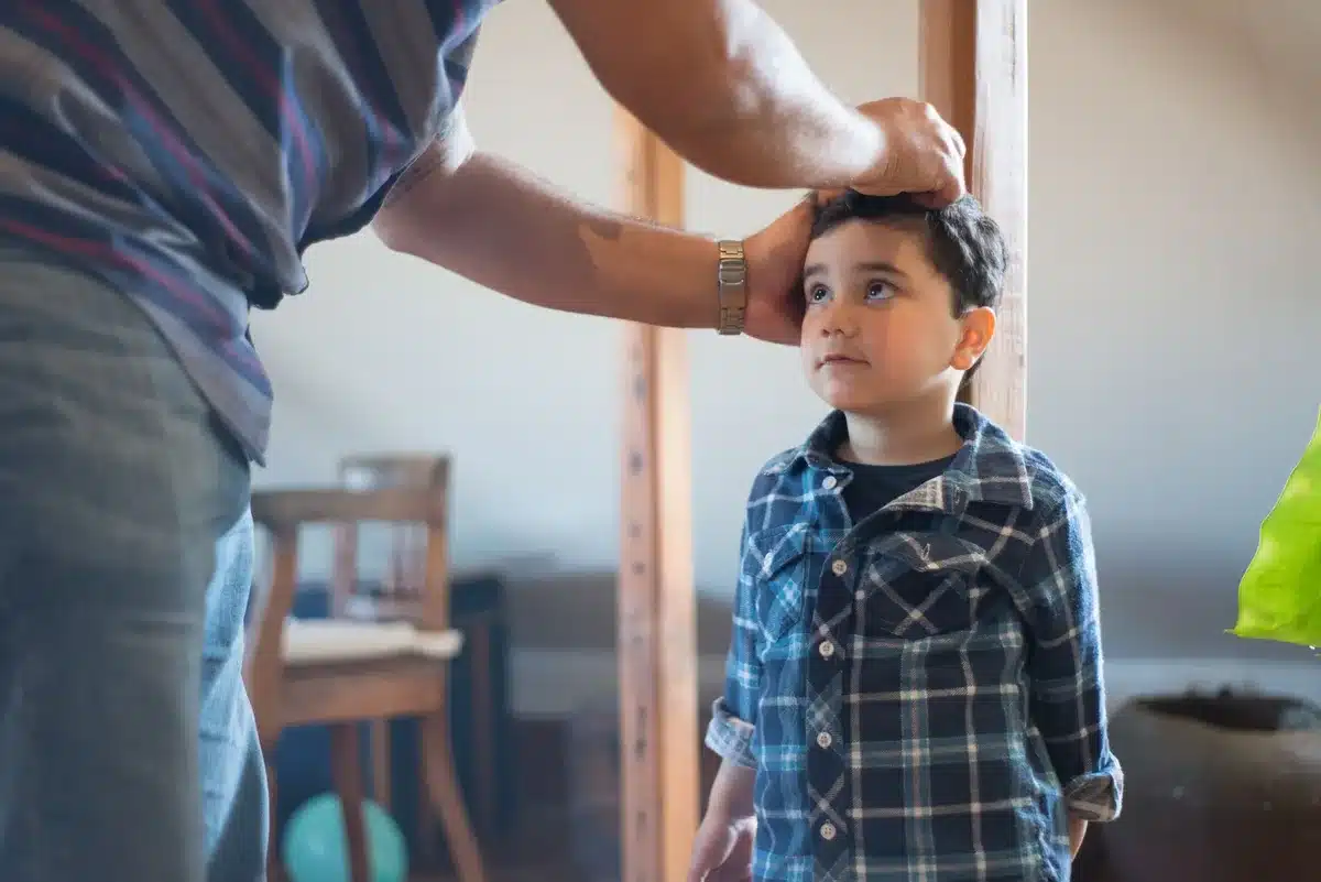 Médecin mesurant la taille d'un enfant sur une toise de croissance calibrée