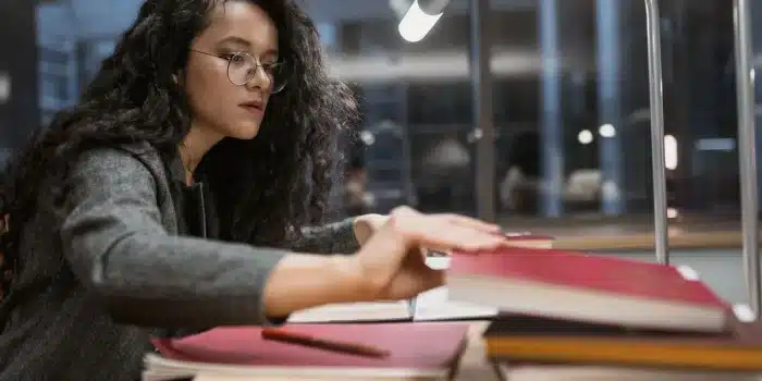 Étudiant en psychologie révisant ses cours dans une bibliothèque universitaire avec des livres et des notes