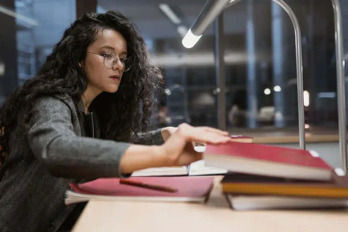 Étudiant en psychologie révisant ses cours dans une bibliothèque universitaire avec des livres et des notes