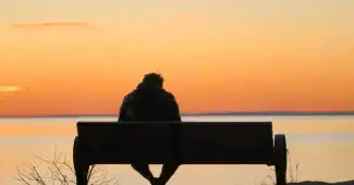 Silhouette d'une personne isolée, visage tourné, entourée de figures familiales floues en arrière-plan.