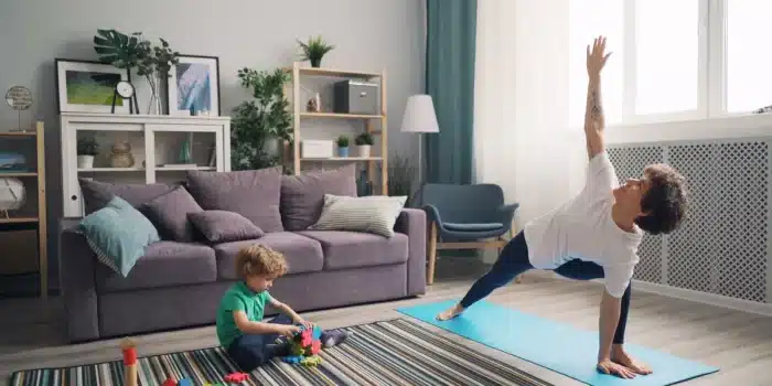 Maman faisant du sport à domicile avec son enfant qui joue à proximité