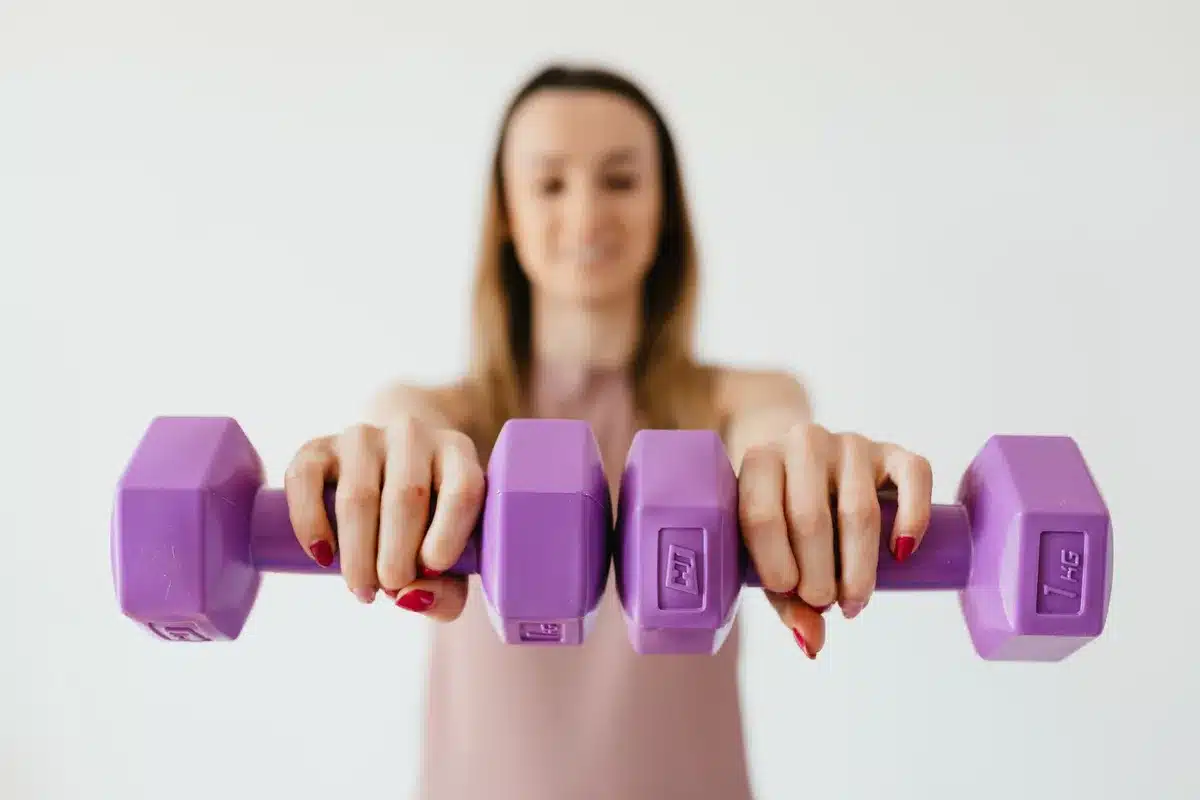Femme en train de faire des exercices de renforcement musculaire avec des poids légers