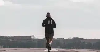 Personne marchant rapidement sur un sentier ensoleillé dans un parc, bras en mouvement, lumière du matin