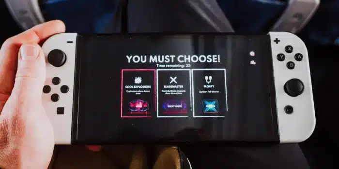Main d'une personne tenant une manette de jeu devant un écran luminescent affichant des récompenses virtuelles