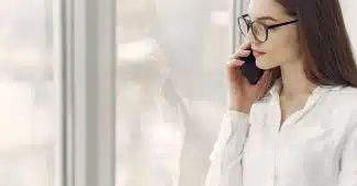 Main silhouetted against soft light pressing a phone screen to block a contact