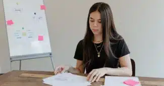 Une femme consulte des documents de gestion et des tableaux financiers sur un bureau