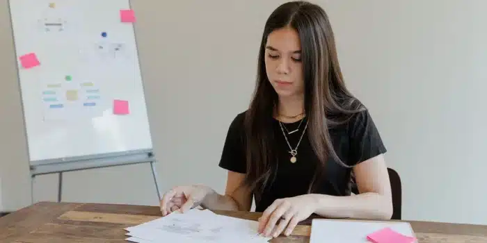 Une femme consulte des documents de gestion et des tableaux financiers sur un bureau