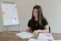 Une femme consulte des documents de gestion et des tableaux financiers sur un bureau