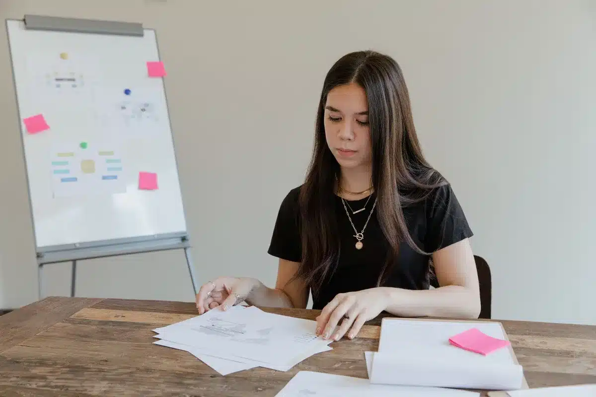 Une femme consulte des documents de gestion et des tableaux financiers sur un bureau