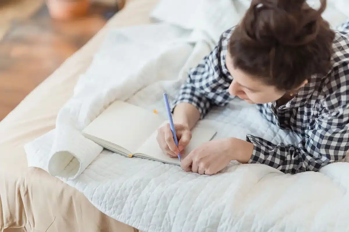 Personne écrivant dans un journal pour explorer ses émotions et besoins