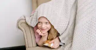 Enfant assis seul dans un coin calme et apaisant, enveloppé d'une couverture, cherchant du réconfort.