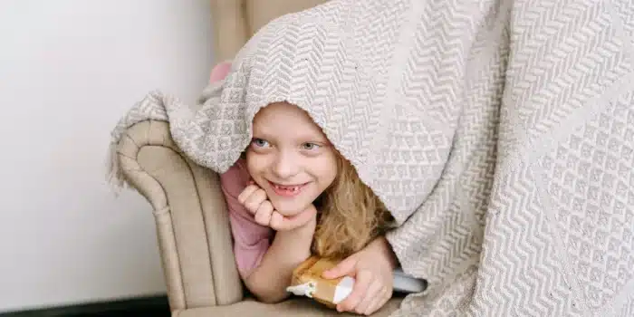 Enfant assis seul dans un coin calme et apaisant, enveloppé d'une couverture, cherchant du réconfort.