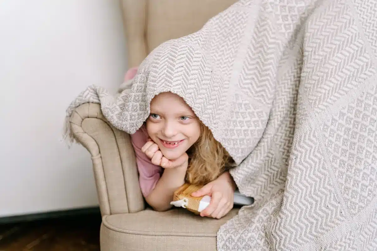 Enfant assis seul dans un coin calme et apaisant, enveloppé d'une couverture, cherchant du réconfort.