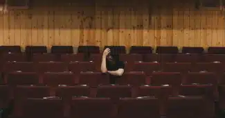 Personne assise seule, semblant fatiguée, dans un environnement calme et lumineux