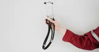 Main tremblante d'une personne pendant une urgence médicale avec une horloge en arrière-plan