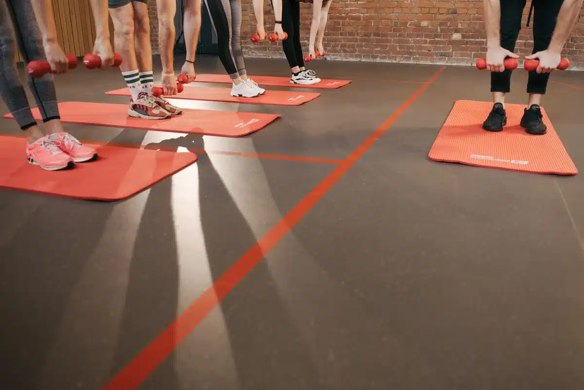 Personne en cours collectif de fitness, levant les bras dans une ambiance de groupe énergique.