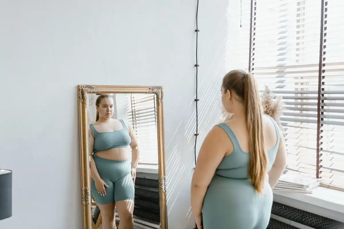 Personne regardant son reflet avec sérénité, représentant l'acceptation du corps et la confiance en soi.