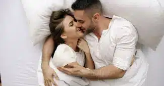Couple enlacé dans une chambre calme, évoquant la tendresse et la complicité.