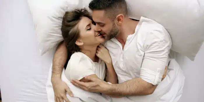 Couple enlacé dans une chambre calme, évoquant la tendresse et la complicité.