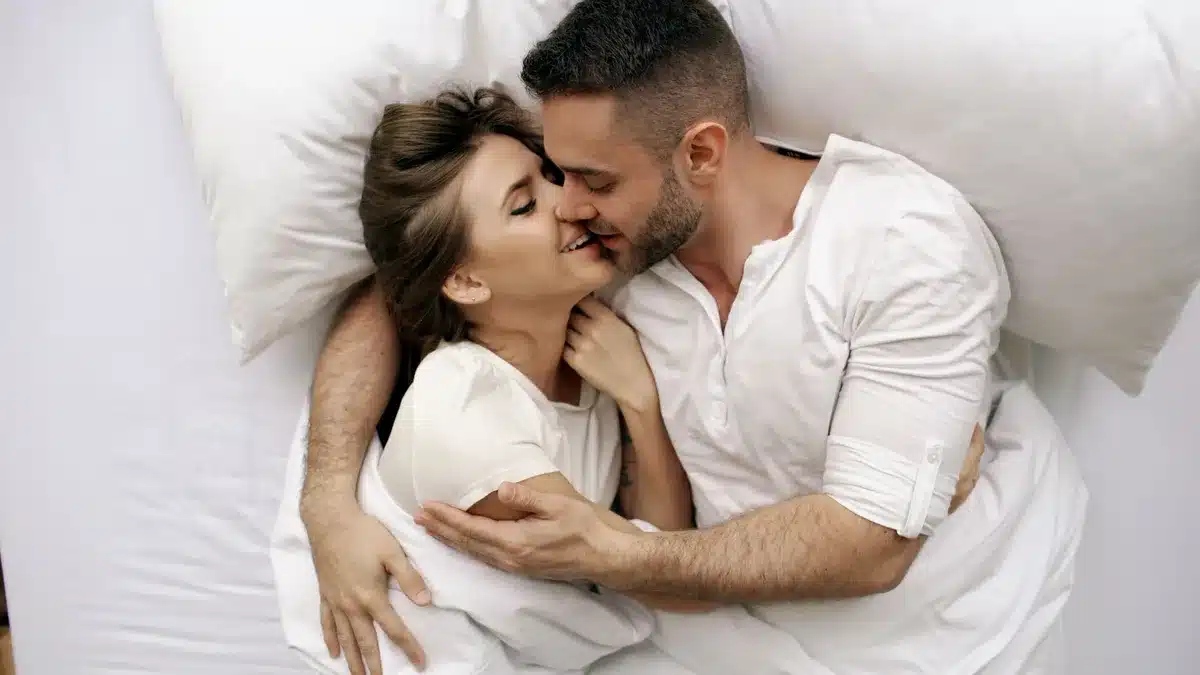 Couple enlacé dans une chambre calme, évoquant la tendresse et la complicité.