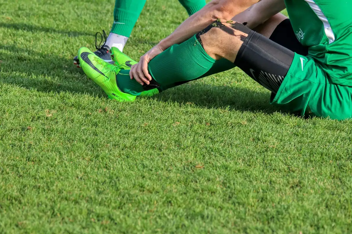 Personne en tenue de sport regardant sa cheville avec douleur après l'entraînement