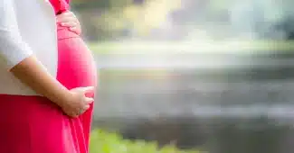 Silhouette d'une femme enceinte dans une salle d'attente de maternité, tenant un dossier