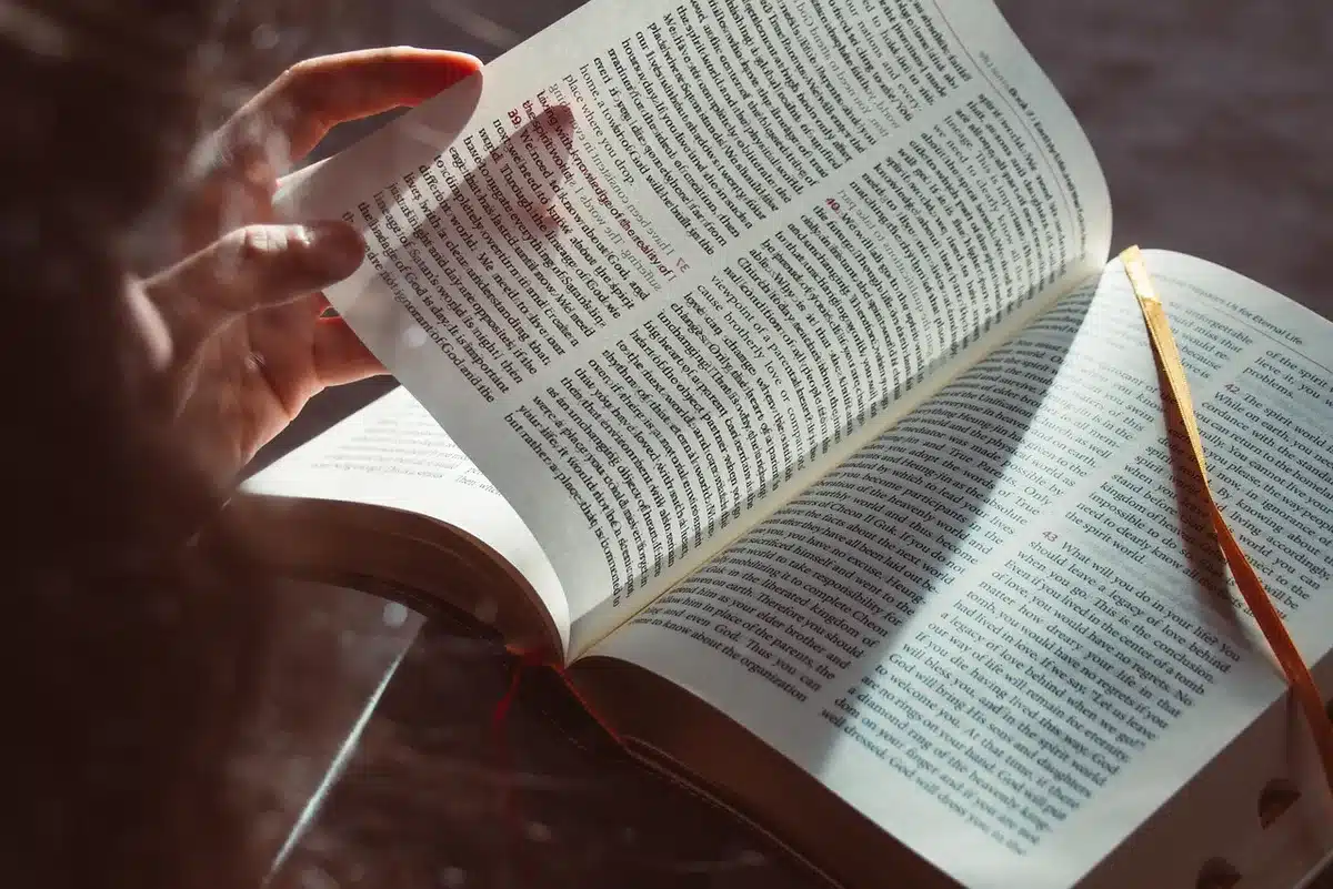 Enfant lisant et montrant du doigt un livre dans une pièce lumineuse