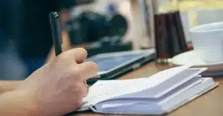 Mains anonymes posant une tasse de thé près d'un pilulier et d'un carnet sur une table