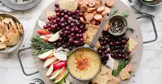 Assiette anonyme de fromage, bol d'oléagineux et pomme sur une table au crépuscule