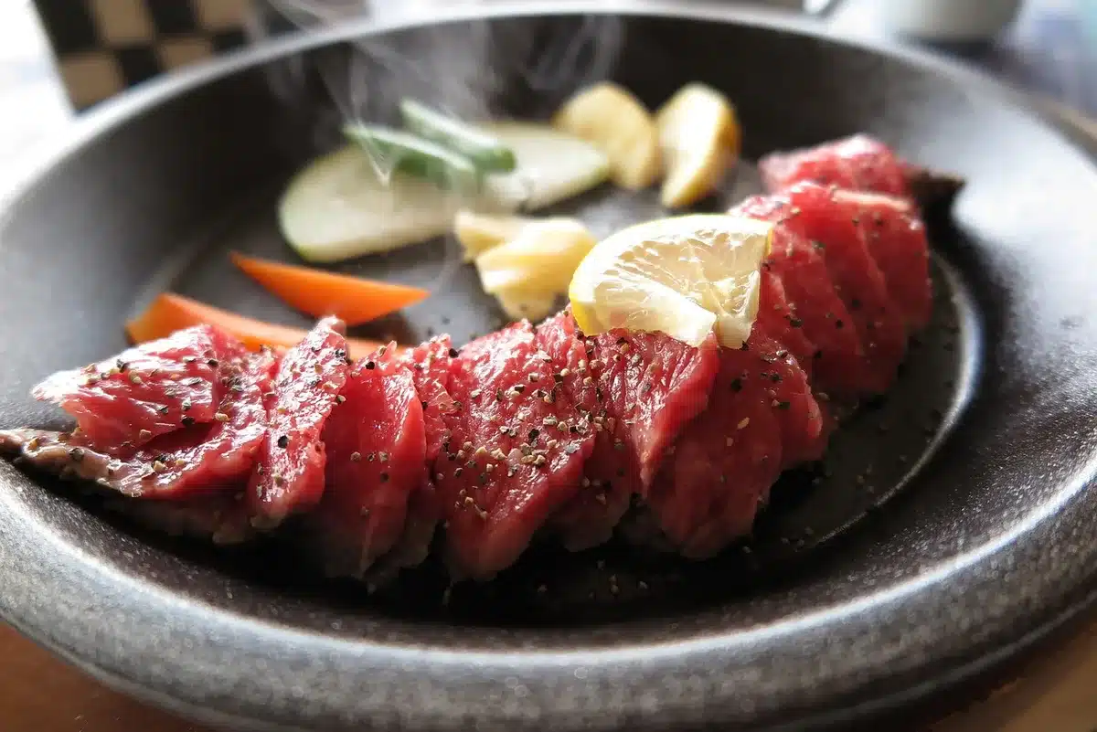 Main retirant la peau d'un poivron grillé sur une planche