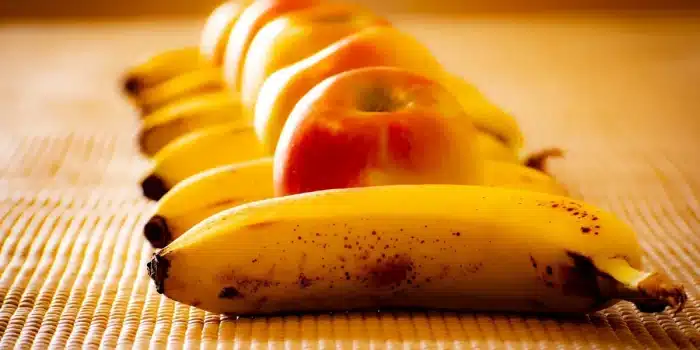 Blender sur un plan de travail en journée, bananes et framboises prêtes à être mixées