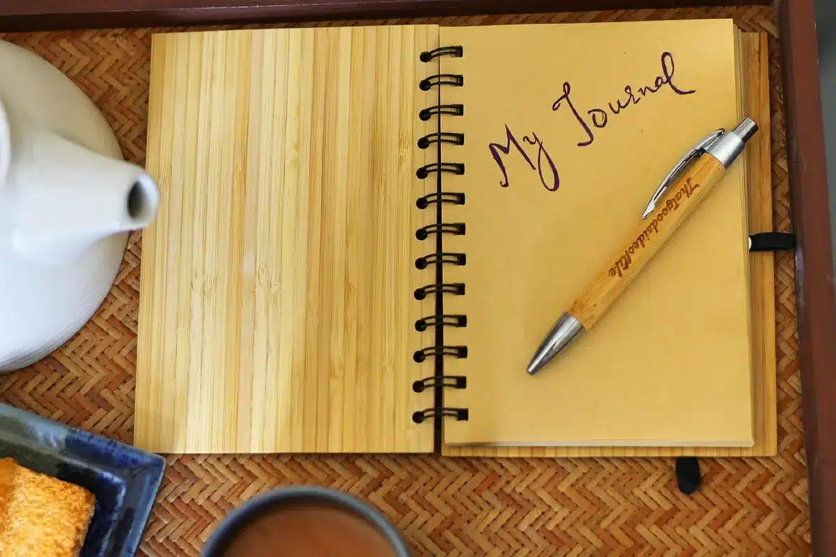 Personne écrivant dans un carnet à une table baignée de lumière