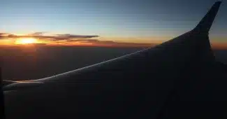 Passager assis dans un avion, mains crispées sur l'accoudoir, regardant par le hublot avec une expression tendue.