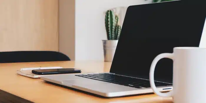 Mains tenant un carnet et un stylo sur un bureau éclairé par la lumière du jour
