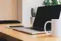 Mains tenant un carnet et un stylo sur un bureau éclairé par la lumière du jour
