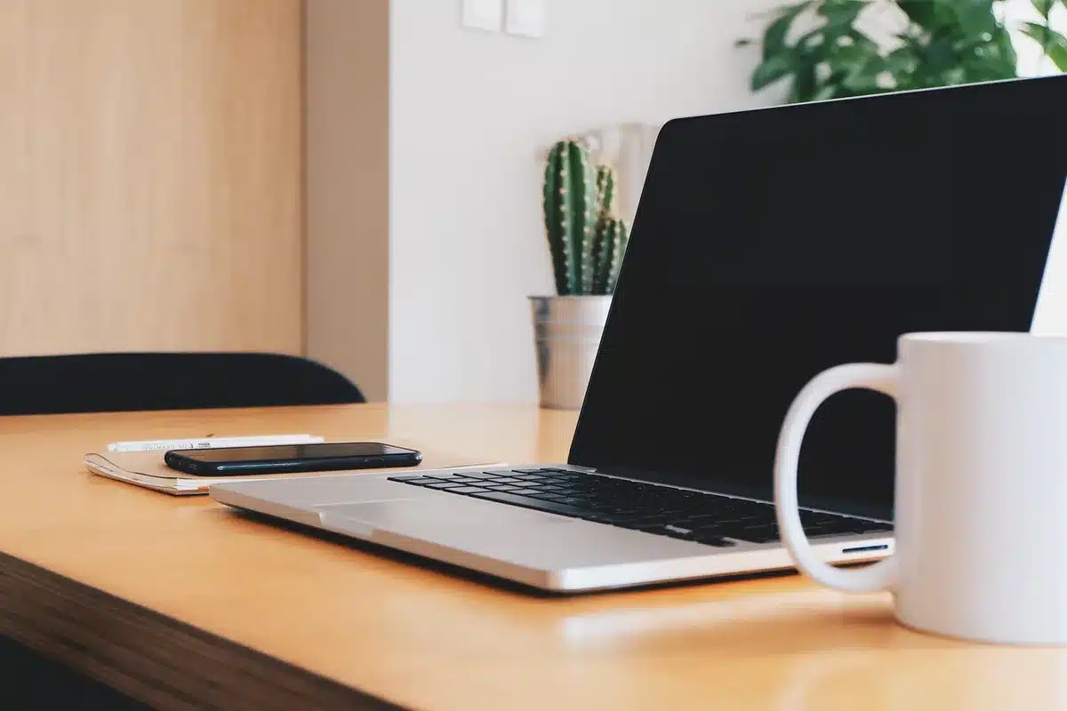 Mains tenant un carnet et un stylo sur un bureau éclairé par la lumière du jour