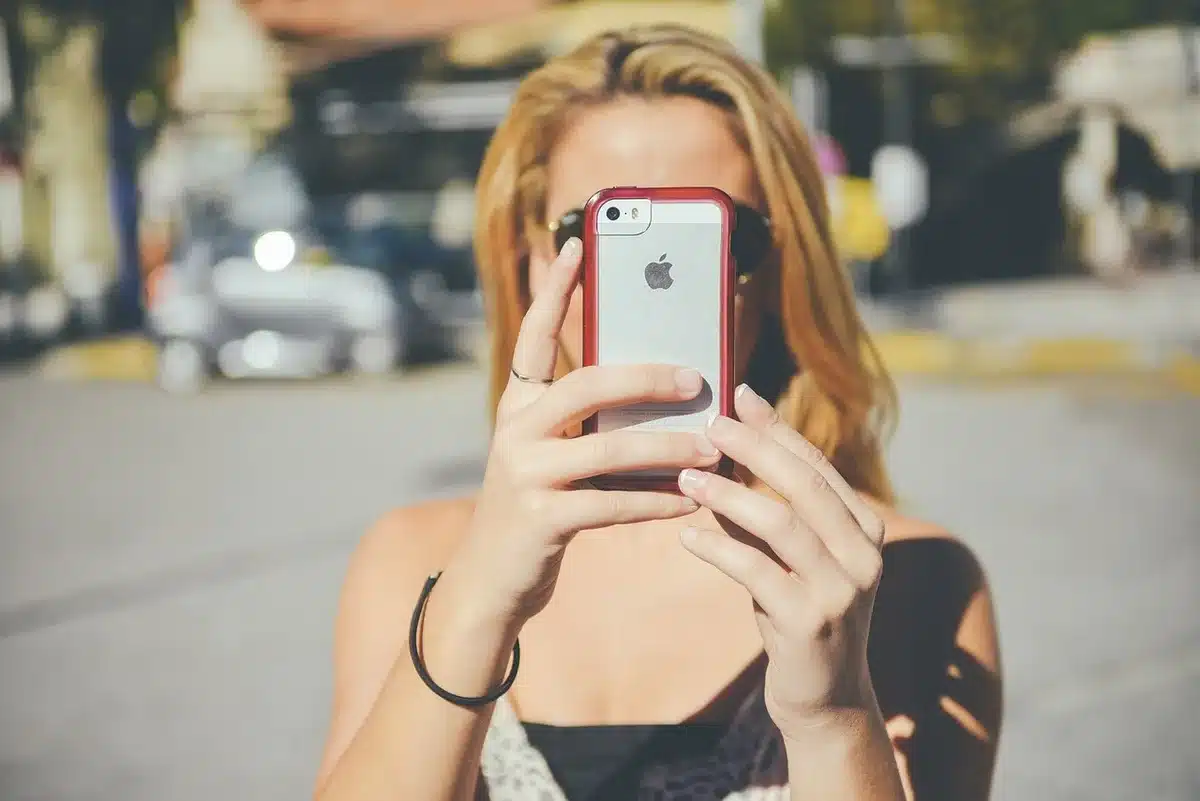 Utilisateur vérifiant les paramètres de confidentialité sur un smartphone près d'une fenêtre