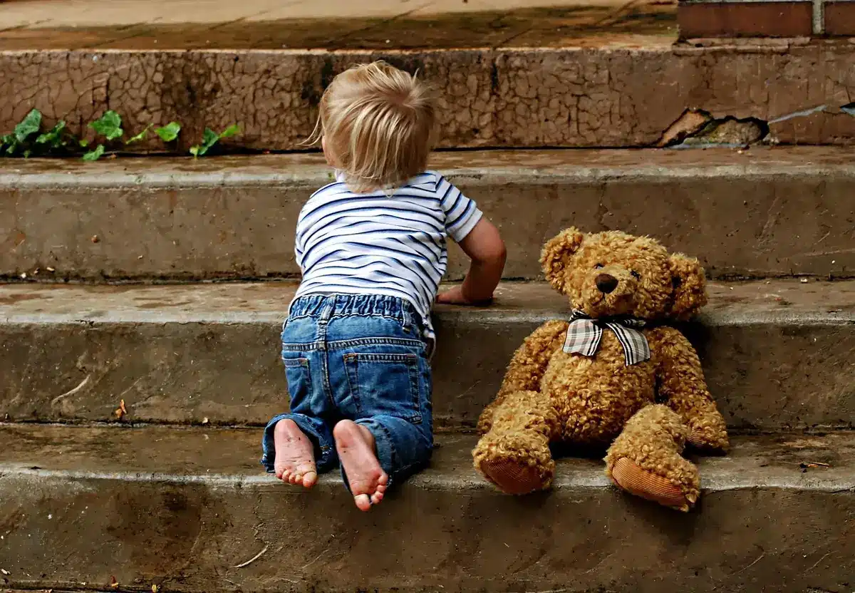 Enfant qui peine à monter les escaliers avec l'aide d'un adulte