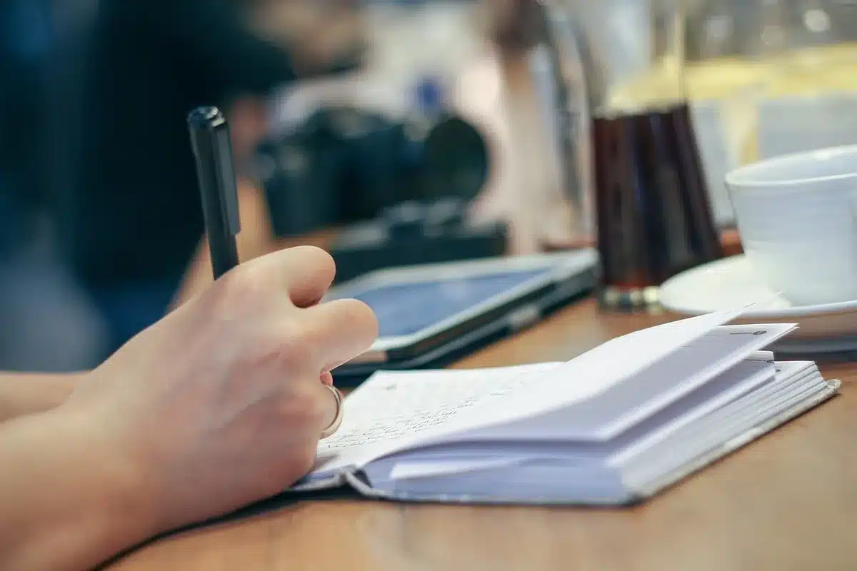 Main écrivant dans un journal pour travailler l'estime de soi