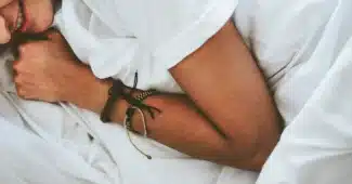Personne anonyme appliquant une crème sur l'avant-bras près d'un lit en plein jour