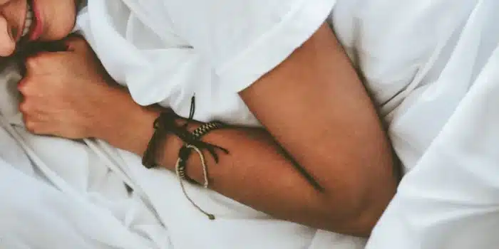 Personne anonyme appliquant une crème sur l'avant-bras près d'un lit en plein jour