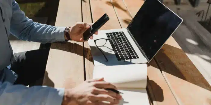 Smartphone posé sur un rebord de fenêtre avec pièces de réparation et carnet, lumière du jour