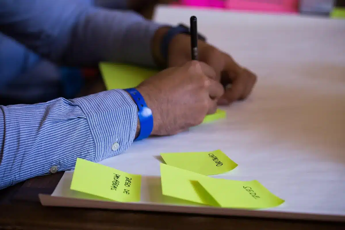 Main écrivant des phrases courtes et neutres sur un carnet